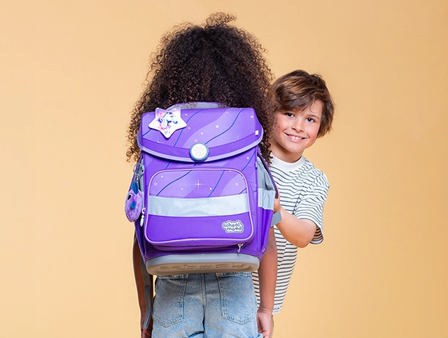 Kind schaut an anderem Kind mit Schulranzen auf dem Rücken vorbei