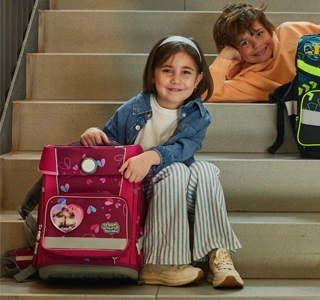 Zwei Kinder sitzen auf einer Treppe und haben jeweils einen Schulranzen vor sich